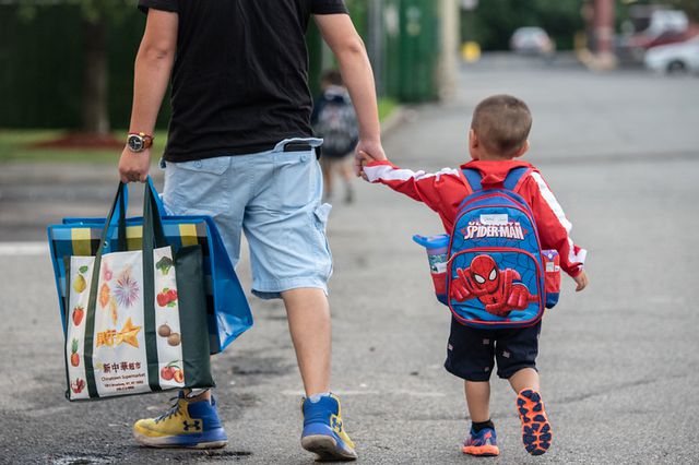 A little boy wearing a Spider-Man backpack walks with an adult during the first day of school in September 2019. Schools Chancellor Richard Carranza said child services will not be called if parents don't have access to a device or adequate WiFi for remote learning.
